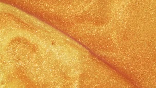 Sable doré coloré se déplace organiquement dans un liquide coloré en macro 