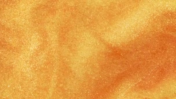 Sable doré coloré se déplace organiquement dans un liquide coloré en macro 