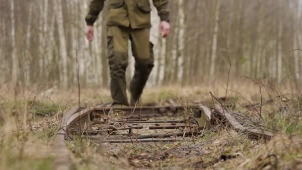 Jovem caminha ao longo dos trilhos ferroviários na floresta de outono — Vídeo de Stock