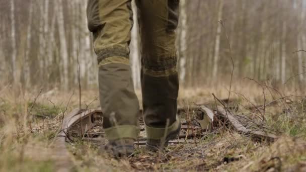 Молодой человек ходит по железнодорожным рельсам в осеннем лесу — стоковое видео