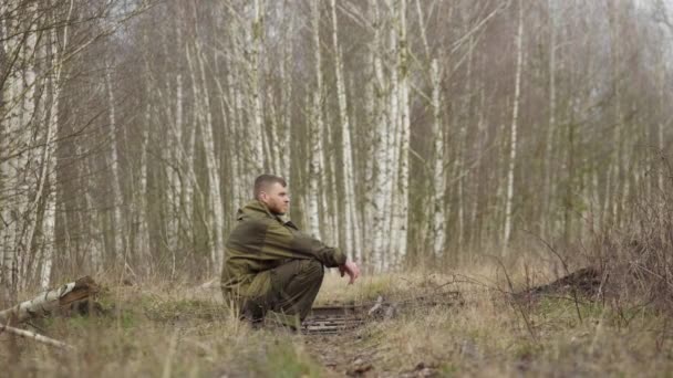 Fehér férfi ül az erdőben a vasúti síneken, ősszel — Stock videók