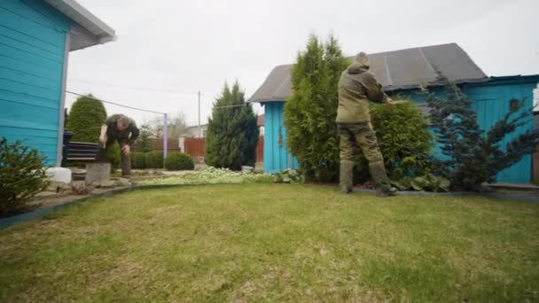 Klónozott kaukázusi férfiak dolgoznak együtt a kertben, felhős, nyári napon — Stock videók