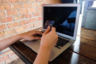 Bağlantılı alışveriş kredi kartı basılı tutup, dizüstü bilgisayar kullanarak genç kadın