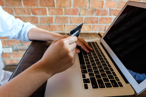 Молодая женщина держит кредитную карту и с помощью ноутбука, покупки onlin
