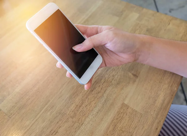 Ahşap masa üzerinde cep telefonu kullanan kadın yakın çekim