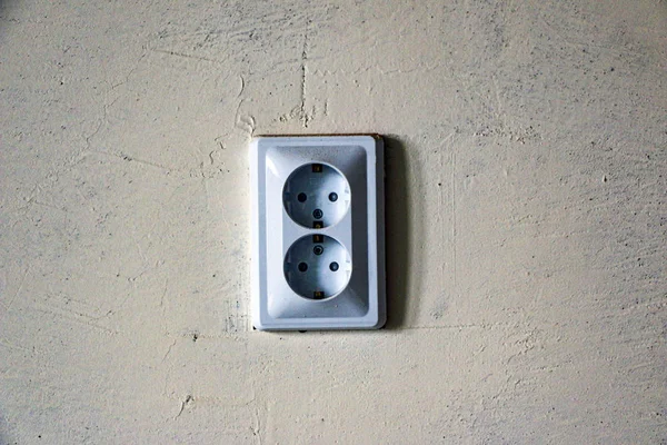 electrical outlets and switches made of white plastic on  wall in  room of apartment or office, during repair.
