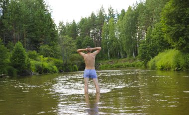 Sırtı sığ, sık, yeşil bir ormanla çevrili bir nehrin sularında duran ince, esmer genç bir adam. İnsanlardan soyutlanmış, doğayla bütünlük ve rahatlama..