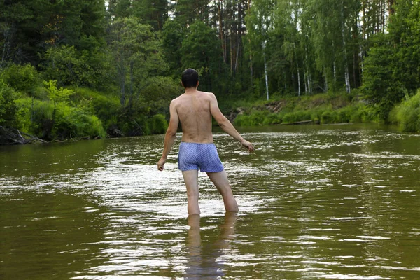 一个身材矮小 身材矮小的黑发男子 后背挺立在一条被茂密的绿林环绕的浅水河中 在与人隔离的情况下与自然的放松和统一 — 图库照片