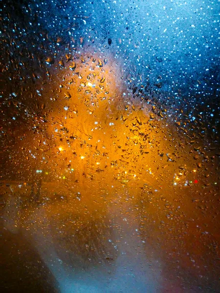 창문에 빗방울이 떨어지고 뒤에는 칠흑같은 도시가 하늘의 눈물이 흘러내린다 창문에 — 스톡 사진