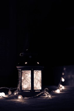 Tatil tebrik kartı veya arka plan. Noel ışıkları ve mum fener koyu arka plan üzerinde. Noel evde. Yeni yıl tatil şablonu.