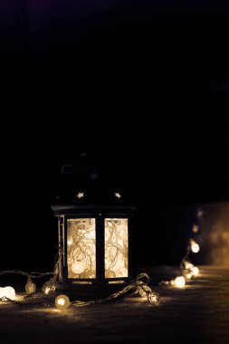 Tatil tebrik kartı veya arka plan. Noel ışıkları ve mum fener koyu arka plan üzerinde. Noel evde. Yeni yıl tatil şablonu.