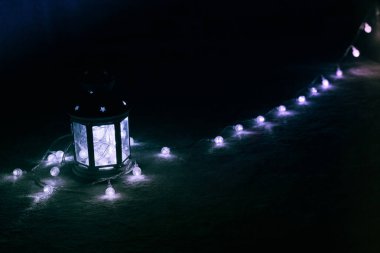 Tatil tebrik kartı veya arka plan. Noel ışıkları ve mum fener koyu arka plan üzerinde. Noel evde. Yeni yıl tatil şablonu.