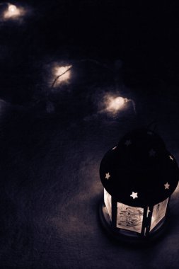 Tatil tebrik kartı veya arka plan. Noel ışıkları ve mum fener koyu arka plan üzerinde. Noel evde. Yeni yıl tatil şablonu.