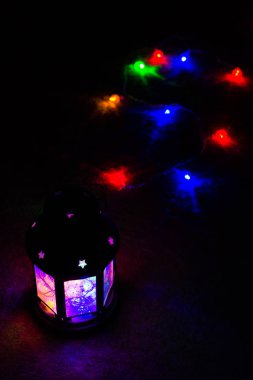 Tatil tebrik kartı veya arka plan. Noel ışıkları ve mum fener koyu arka plan üzerinde. Noel evde. Yeni yıl tatil şablonu.