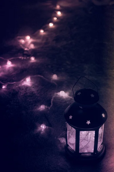 Urlaubsgrußkarte oder Hintergrund. Weihnachtsbeleuchtung und Kerzenlaterne auf dunklem Hintergrund. Weihnachten zu Hause. Vorlage für das neue Jahr Urlaub. — Stockfoto