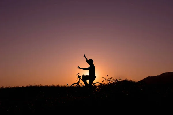 Silhueta de pessoa feliz na bicicleta no pôr do sol natural — Fotografia de Stock
