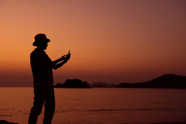 Silueta humana usando un teléfono inteligente en Sunset at Beach —  Fotos de Stock