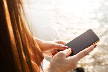 Yaz plaj üzerinde akıllı telefon kullanan kadın