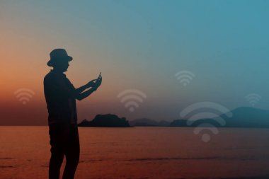 İnsan silüeti plajda akıllı telefonu üzerinden internet kullanımı