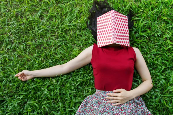 Žena ležela na zelené trávě s knihou v létě — Stock fotografie
