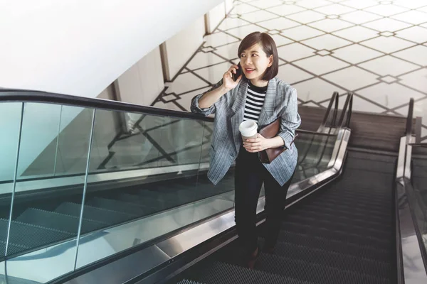 Робоча жінка розмовляє через смартфон під час ескалатора — стокове фото