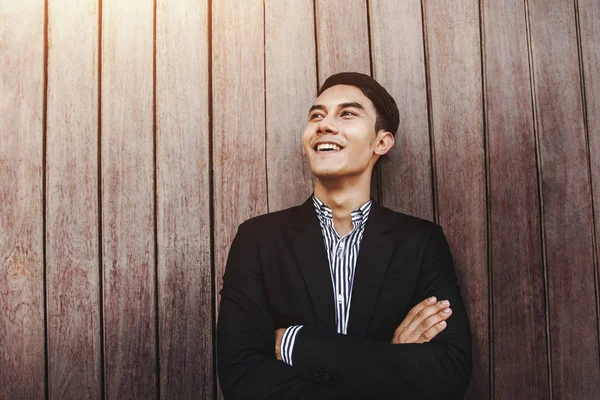 Jovem Felicidade e mente positiva homem de negócios cruzou os braços com rosto sorridente e à procura de sucesso no fundo da parede prancha de madeira, tom quente — Fotografia de Stock