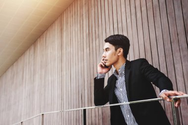 Genç Asyalı işadamı konuşmak yolu ile ciddi yüz ile akıllı telefon