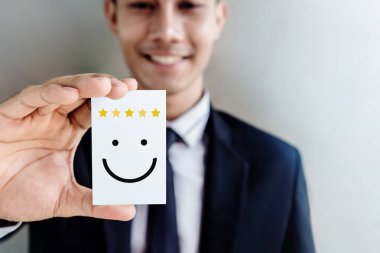 Müşteri deneyimi kavramı, mutlu gülen yüz ve 5 Star Rating kartı duyduğu memnuniyeti için tutan işadamı