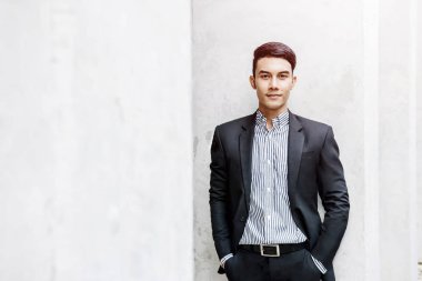 Akıllı resmi kıyafetli Asyalı işadamı kameraya bakarak ve dış binada gülümseyen