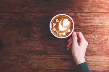 Cafe kavram, bir sıcak Latte Kahve fincanı ahşap masa, kentsel insanların yaşam tarzı üstten görünüm üzerinde tutan el rahatlatıcı rahat
