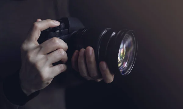 Молодая женщина-фотограф использует камеру для фотографирования. Тёмный тон — стоковое фото
