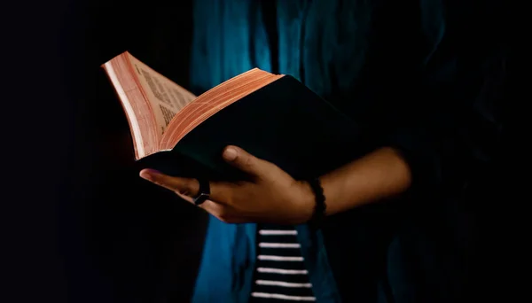 Concepto de lectura. Person Holding Open Bible Book on Hand (en inglés). Oscuro —  Fotos de Stock