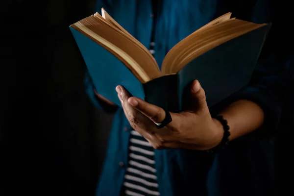 Concepto de lectura. Person Holding Open Bible Book on Hand (en inglés). Oscuro —  Fotos de Stock