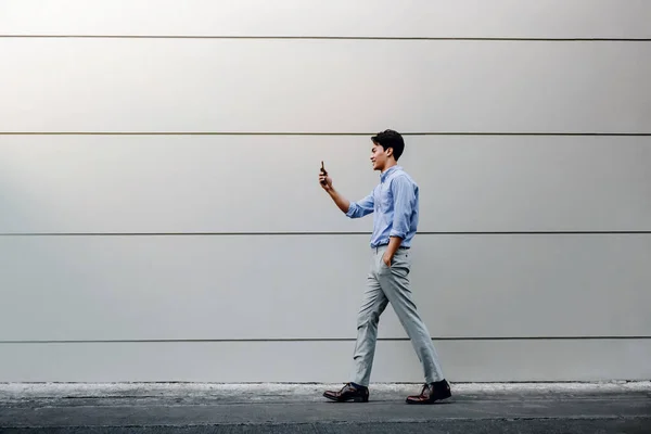 Felice giovane uomo d'affari in abbigliamento casual utilizzando il telefono cellulare mentre — Foto Stock