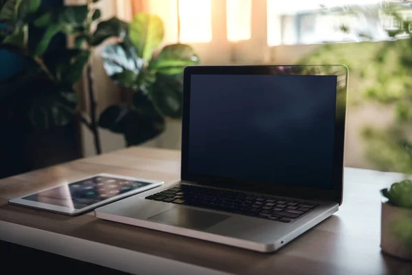 笔记本电脑和平板电脑放在木制桌子上 在家工作 设有窗户灯和绿色植物的舒适工作环境 — 图库照片