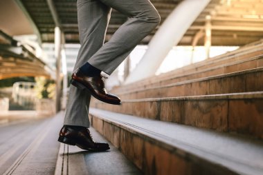 Kariyer Konseptinde motivasyon ve meydan okuma. Adımlarını başarıya doğru atıyor. İş adamının Merdivenden Yukarı Çıkışı 'nın alt bölümü. Arka plan olarak Modern Şehir