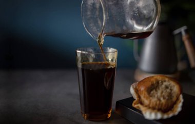 Pencereden sabah güneşinin gölgesinde sıcak kahveyi masaya dökmek. Zen ve Cozy Living. Muffin ve Kettle ile çevrili.