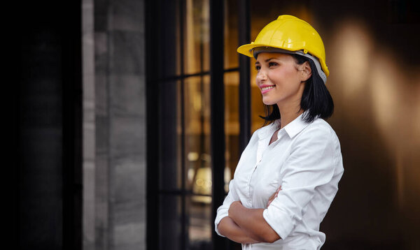 Portrait of a Confident Construction Engineer Woman. Smiling and Looking away. Standing in front of the Modern Office Building