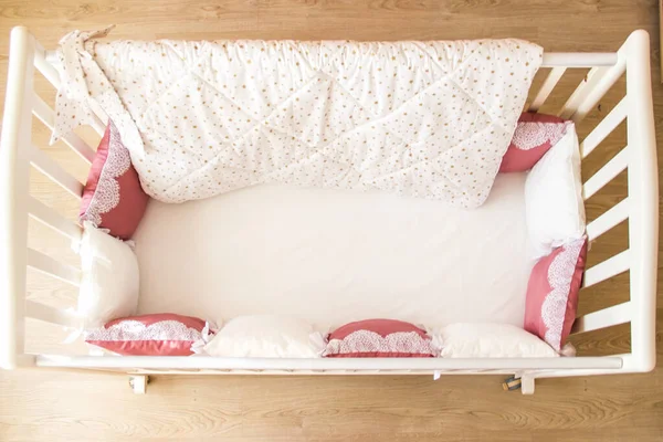 Детская кроватка с белыми и бургундскими подушками со шнурками — стоковое фото