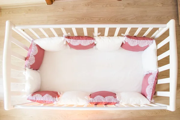 아기 침대에 있는 흰색 과부르군 디 색깔의 베개에는 끈 이달려 있다 — 스톡 사진