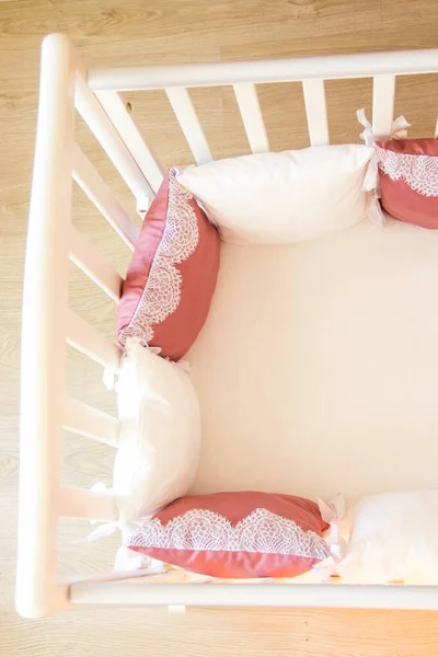 Babybett mit weißen und weinroten Kissen mit Schnürsenkeln — Stockfoto