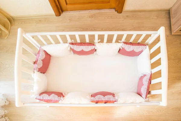 Berço de cama de bebê com almofadas de cor branca e borgonha com atacadores — Fotografia de Stock