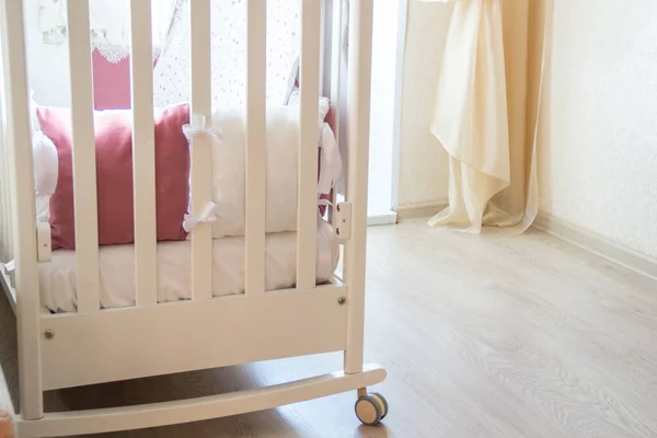 Детская кроватка с белыми и бургундскими подушками со шнурками — стоковое фото