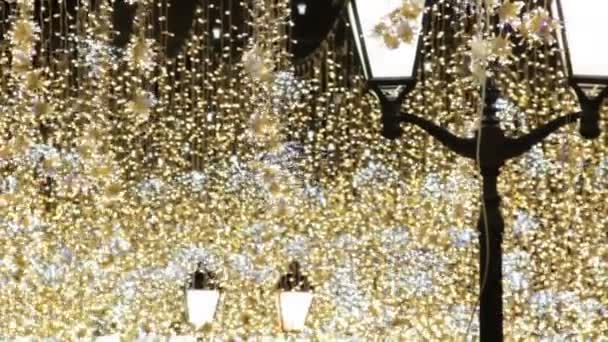 クリスマスと新年の休日は 夜に街の通りで屋外照明 古典的な街路灯で金色のきらめく花輪を振る — ストック動画