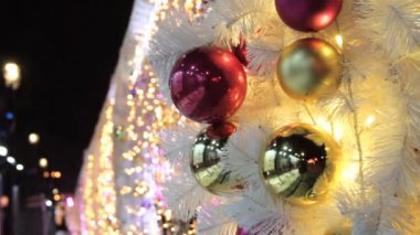 Noel ağacı arkaplanı ve Noel dekorasyonu. Beyaz köknar ağacında altın renkli toplar ve çelenkler. Mutlu yıllar ve Xmas teması. Bulanık, pırıl pırıl çelenk ışıkları, tatil geçmişi..