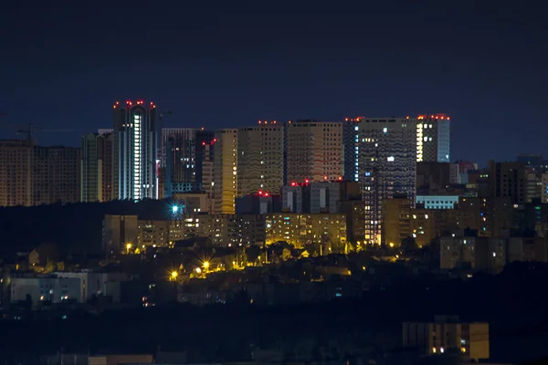 Appartementen in de drukke stad 's nachts, lichten uit. Verschillende hoge en lage gebouwen bekijken vanaf een dak — Stockfoto