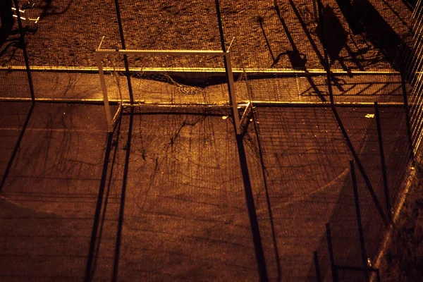 Luchtopname van een leeg sportveld 's nachts in een donkere tuin met lange schaduwen. Eén straatlamp — Stockfoto