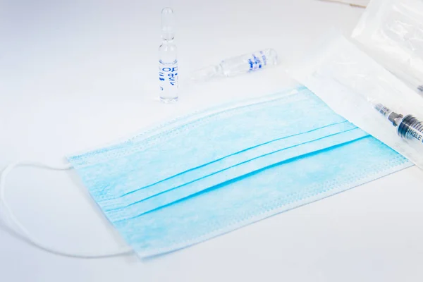 Glass medicine vials,blue mask and syringe unboxed on white back — Φωτογραφία Αρχείου