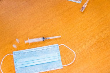 Beyaz arka planda kulaklık takan tıbbi bir maske. Sağlık uzmanları için tıbbi araçlar. Tek kullanımlık şırıngalar.