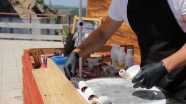 Tanımlanamayan şef, yazın güneşli sıcak bir günde soğuk tabakta Tayland usulü kızarmış dondurma yapıyor. Turist için küçük bir kafe. Arka planda dağ ve yeşil ağaçlar.